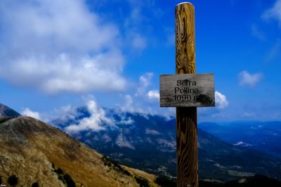 Information sign on wooden post against mountains