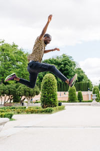 Low angle view of person jumping against sky