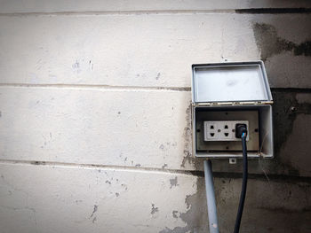 Close-up of old telephone booth against wall