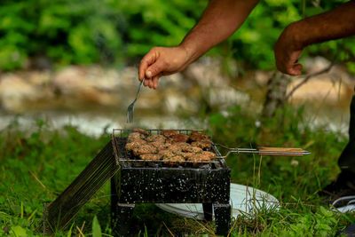 Cropped image of person preparing food on barbecue grill