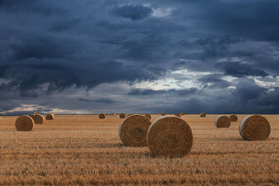 Hay bales on field against sky