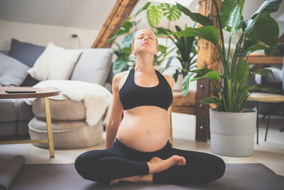 Young beautiful pregnant woman training yoga at home in her living room. motherhood, pregnancy