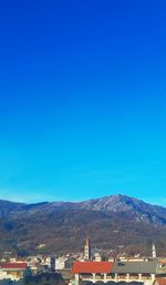 Houses and mountains against clear blue sky