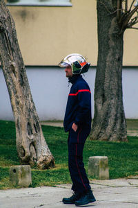 Side view of boy standing by tree trunk