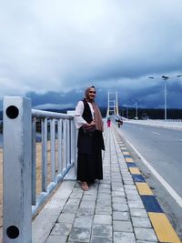 Full length of woman standing on railing against sky