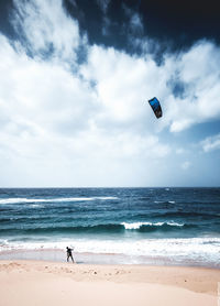 Man paragliding on beach against sky