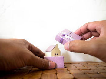 Cropped hand packing model house in box on table