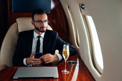 Businessman wearing suit sitting at private jet