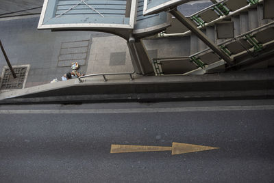 High angle view of man crossing street against building