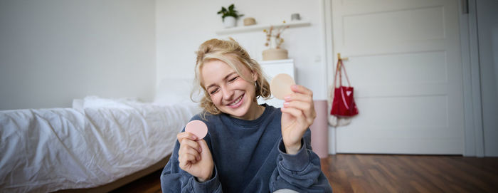 Portrait of smiling young woman using mobile phone while sitting at home