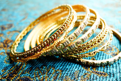 Close-up of gold colored bangles on blue mat