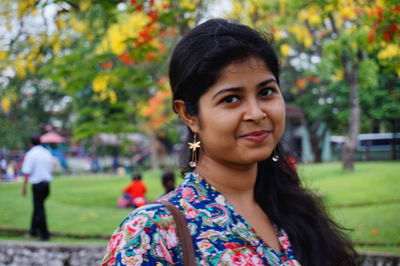 Close-up portrait of smiling beautiful woman standing at park