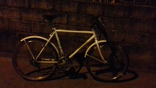 Bicycle on sidewalk against wall