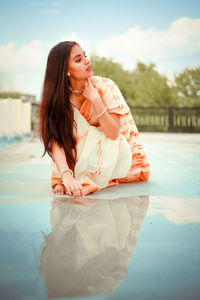 Beautiful young woman in swimming pool against sky