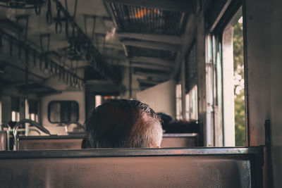 Rear view of man seen through train window