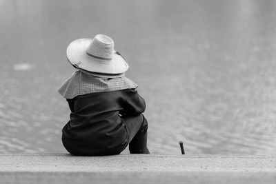 Rear view of woman sitting against wall