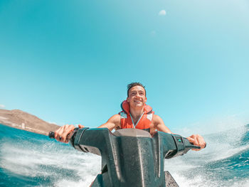 Smiling teenager driving jet ski in sea