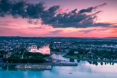 Aerial view of city against cloudy sky at sunset