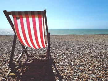 Deck chair on shore at beach during sunny day