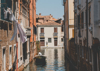 Boats in canal amidst buildings against clear sky