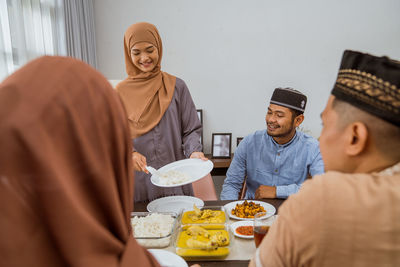 Smiling woman serving food to guests at home