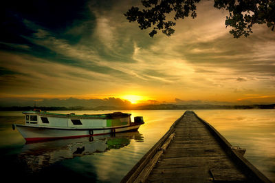 Pier over lake against sky during sunset