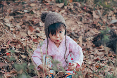 Portrait of cute baby girl crouching on field during winter