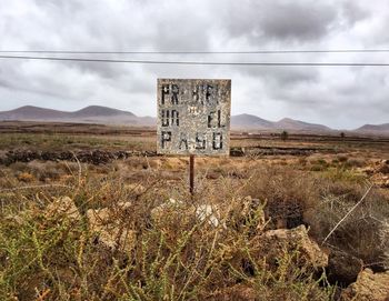 Information sign on field against sky