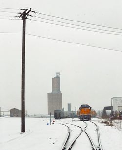 Electricity pylons against sky during winter