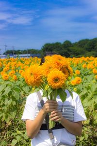 Low angle view of woman holding sunflower in field