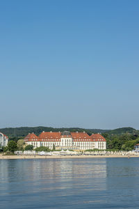Scenic view of lake by building against clear blue sky