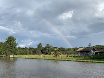 Scenic view of rainbow over lake against sky