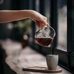 Close-up of hand pouring coffee in glass