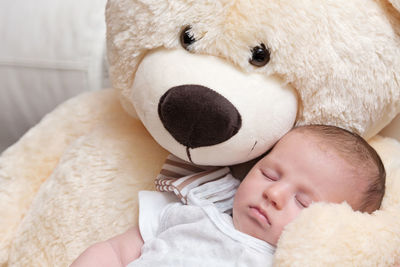 Close-up of baby sleeping with stuffed toy at home