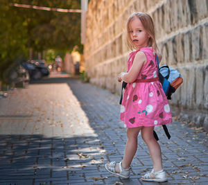 Portrait of cute girl standing on footpath