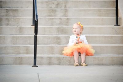 Cute girl holding toy while sitting on steps