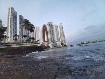 Modern buildings by sea against sky in city