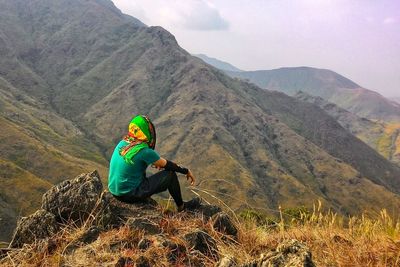 Rear view of woman sitting on mountain