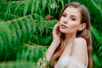 Portrait of young woman against plants