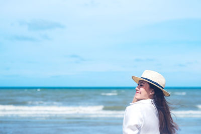 Woman wearing hat on beach against sky