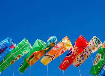 Low angle view of multi colored umbrellas against clear blue sky