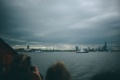 City at waterfront against cloudy sky