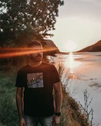 Young man standing on land against sky during sunset