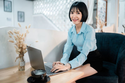 Young businesswoman using laptop while sitting on sofa at home