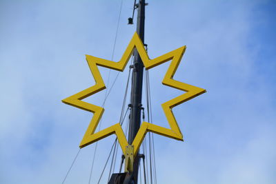 Low angle view of star shape on mast against sky