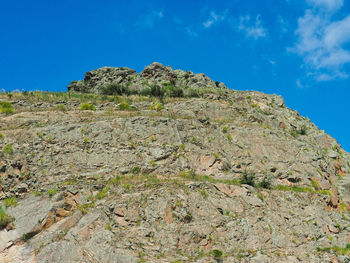 Low angle view of rocky mountain against blue sky