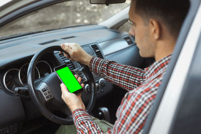 Midsection of man using mobile phone at car
