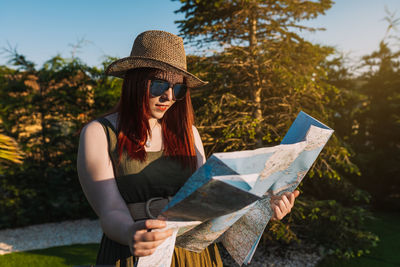 Woman reading map while standing outdoors