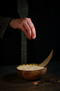 Close-up of hand holding bowl on table