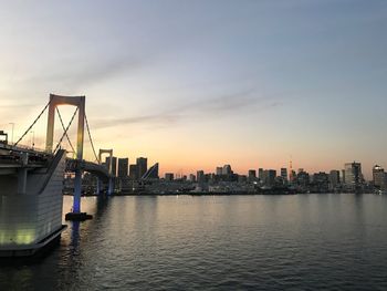 View of suspension bridge in city at sunset